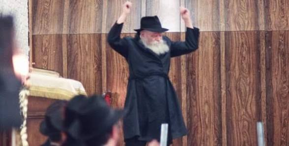The Rebbe encouraging joyful singing at 770 The Lubavitcher Rebbe raising both arms to encourage singing at Chabad headquarters 770